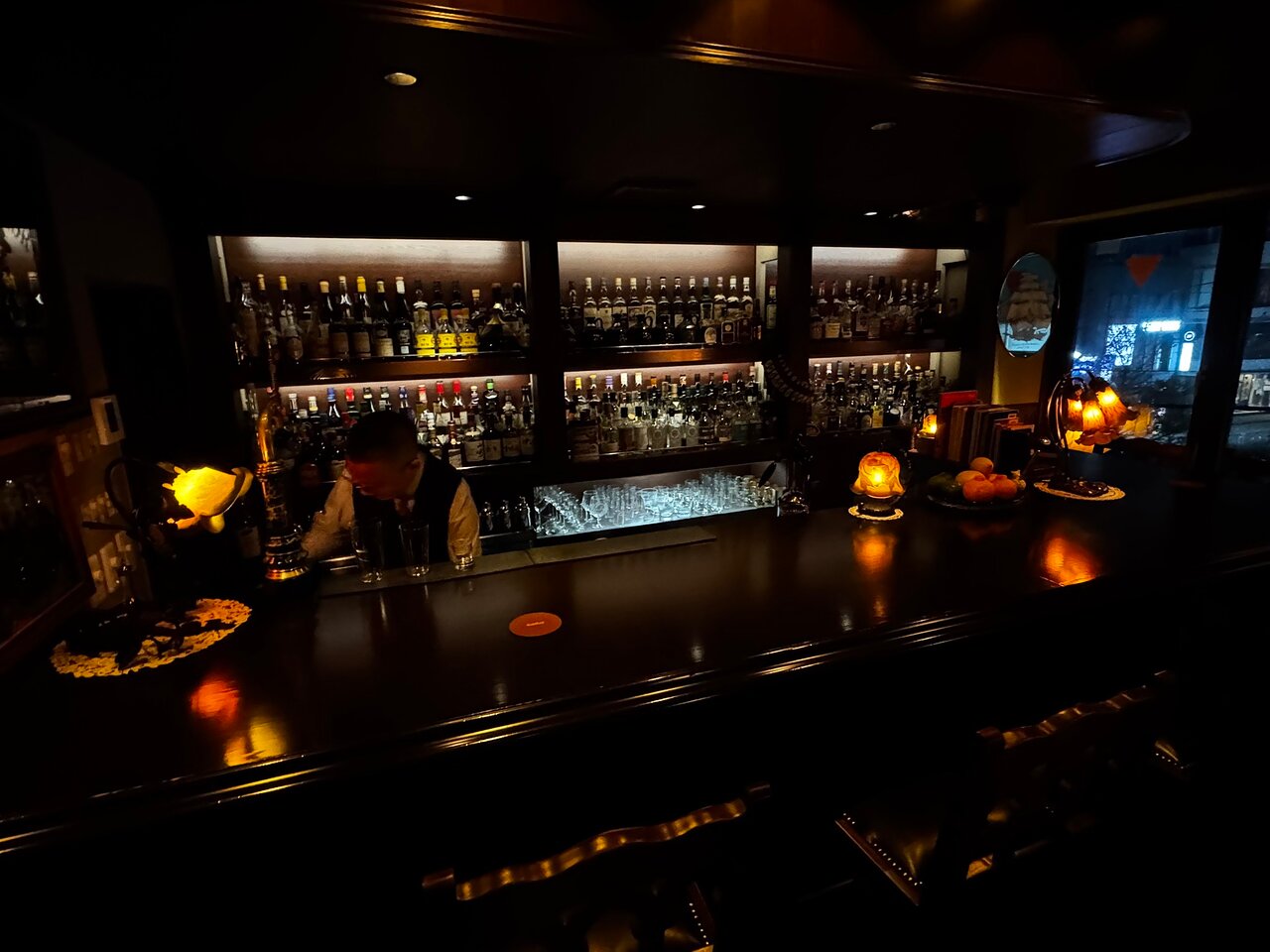 A bartender at work behind a classic dark wood bar counter